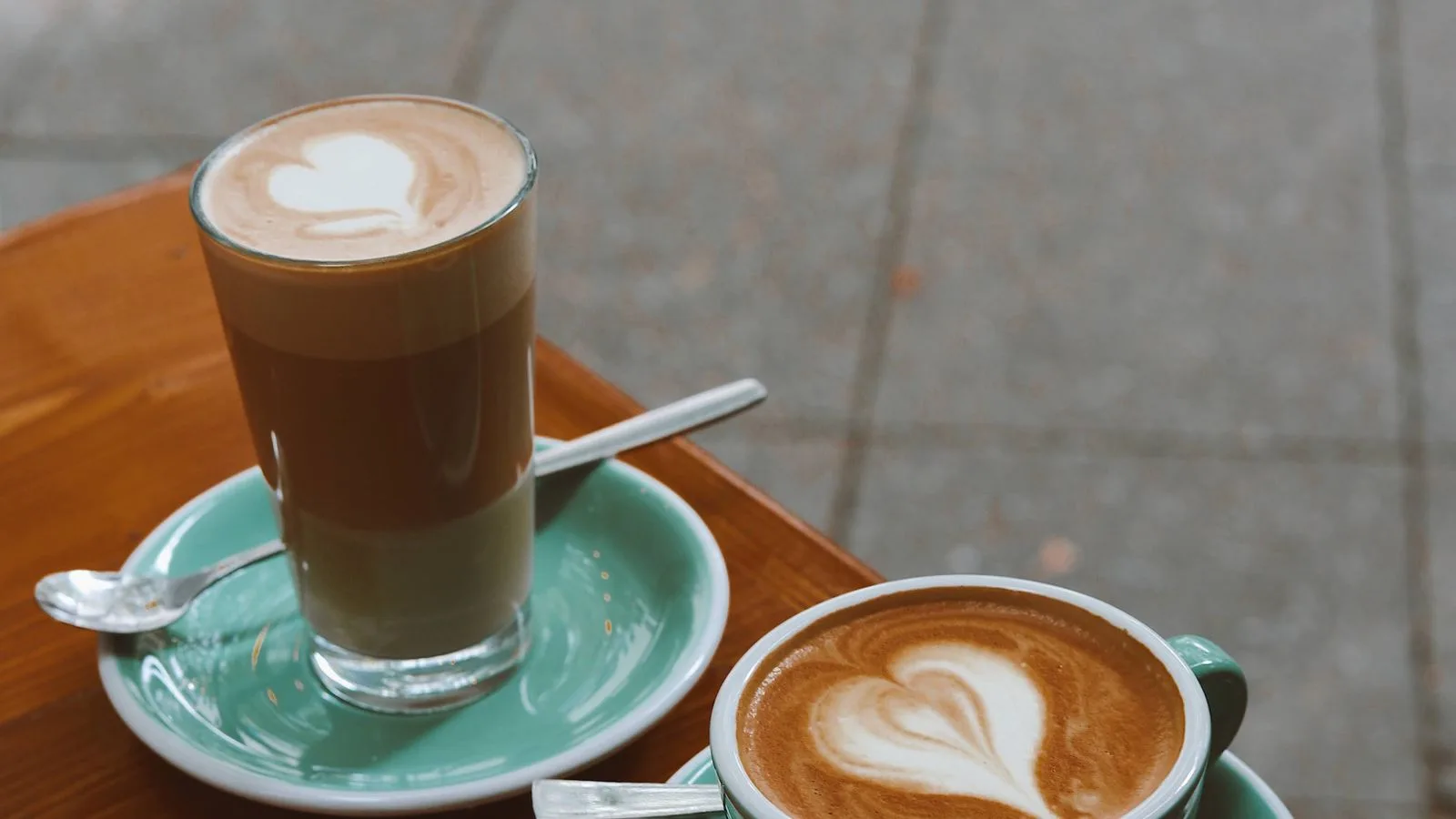 Photo by Chantal Lenting on Pexels Two milk coffees on an outdoor table, one in a clear glass and one in a ceramic cup