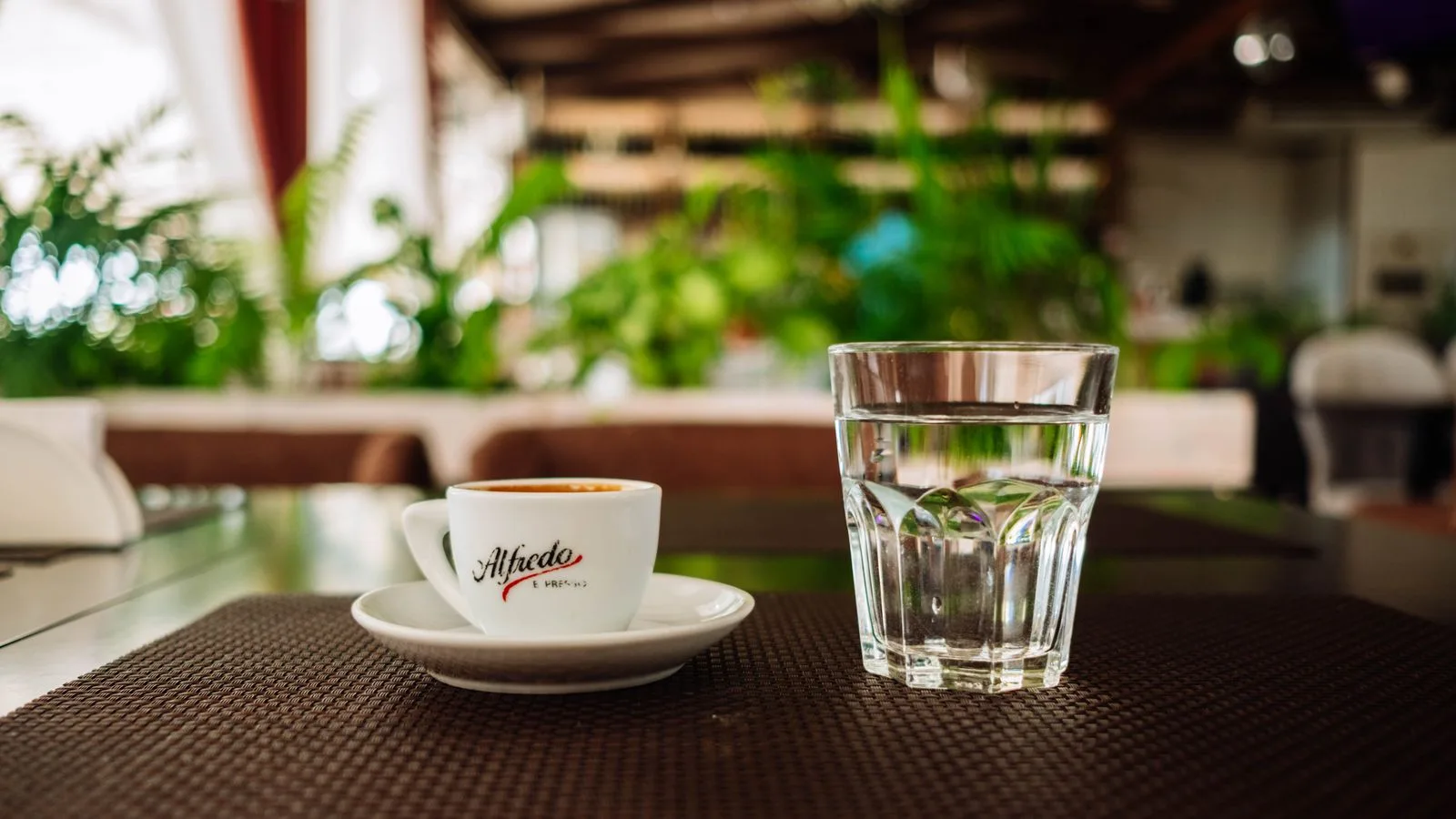 A coffee cup and a glass of water on a café table