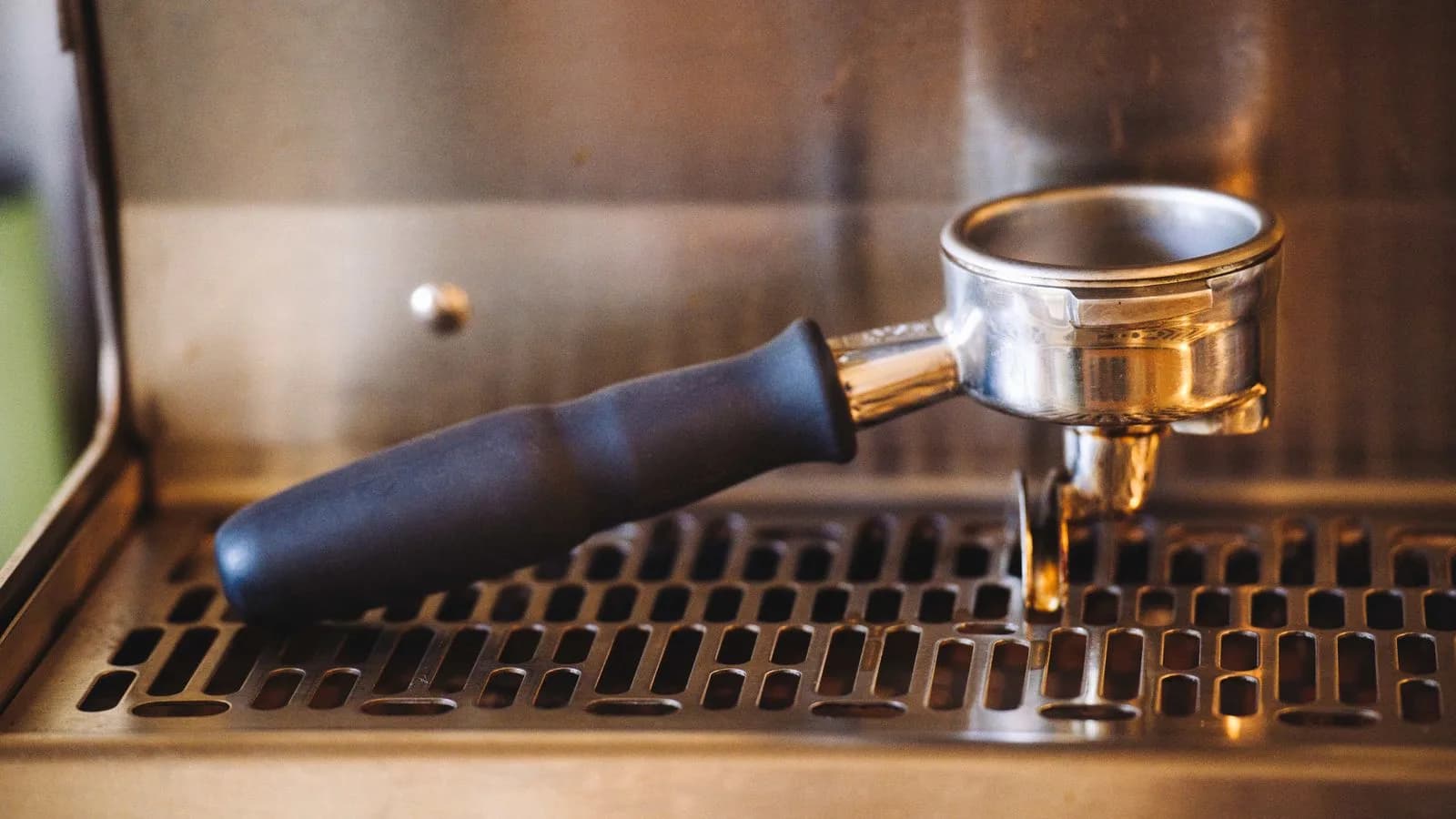 A portafilter resting on an espresso machine drip tray