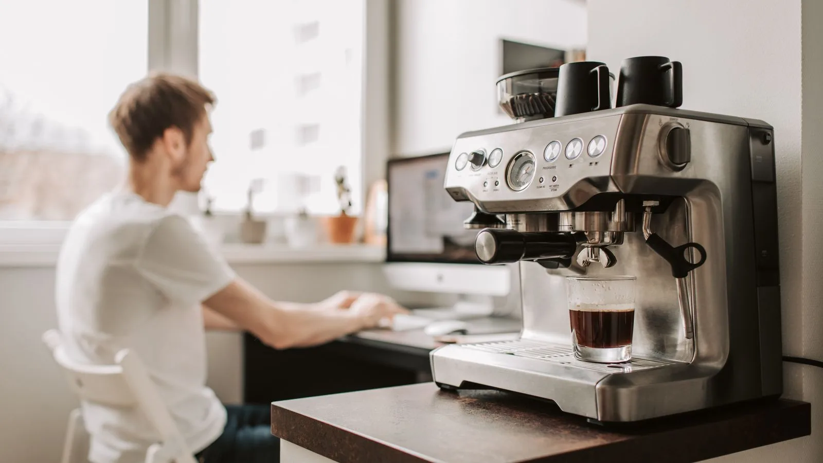 An espresso machine with a built-in grinder on a kitchen counter