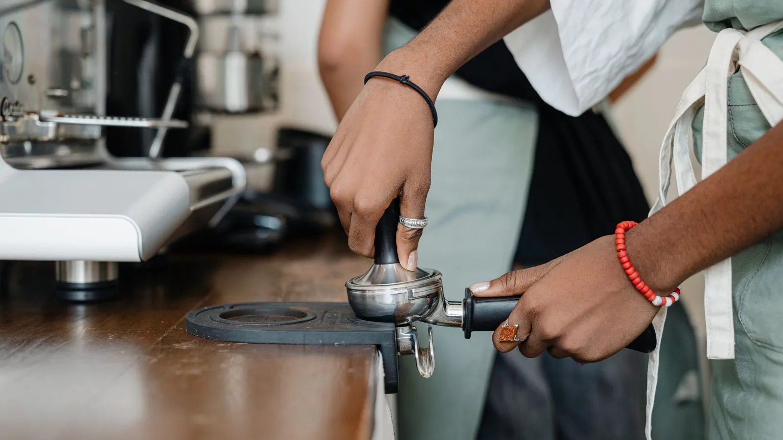 A barista tamping coffee grounds in a portafilter